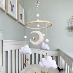 a baby crib with some clouds and stars hanging from it