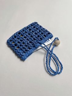 a blue crocheted cell phone case with a cord attached to it on a white surface