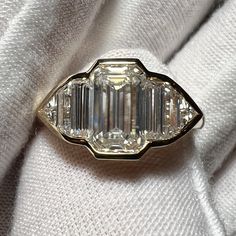 an antique diamond ring with three baguettes in the center on a white cloth