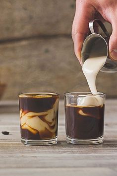 a person pouring coffee into two glasses