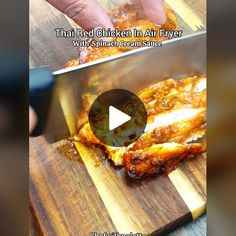 someone is cutting chicken in an air fryer on a wooden board with a knife