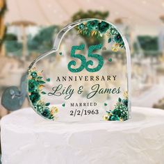 a heart shaped cake topper with the number 55 on it and flowers in green