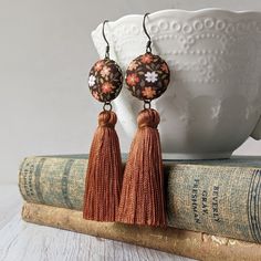 If you're getting ready for fall or just love this boho style color scheme year-round, these lightweight handmade earrings are sure to go with your autumn look. They're made from vintage floral fabric and paired with shimmery burnt orange tassels. Full length - 3 5/8 inches Earring hook - darkened raw brass Earring backing - clear comfortable rubber Similar jewelry: Check out my shop for many more floral and vintage styles! Gift boxes:  Every piece of jewelry comes in a box, making it easy to give as a gift or keep for storage. Questions? Feel free to send me a message for custom requests, shipping details, and more. Bohemian Fall Fashion, 70s Earrings, Thanksgiving Jewelry, Fall Fashion Accessories, Vintage Floral Fabric, Fabric Earrings, Orange Earrings, Fall Earrings, Burnt Orange