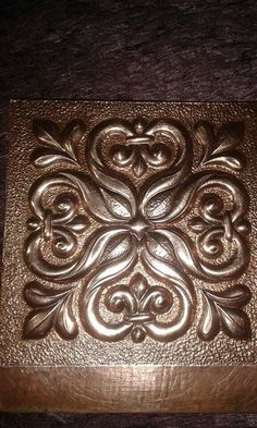 a metal box that is on top of a wooden table and has an intricate design