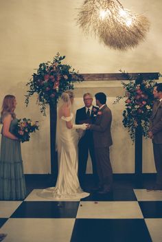 a bride and groom are getting married in front of an altar decorated with floral arrangements