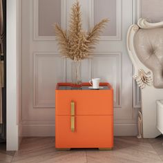 an orange box is sitting in front of a white chair with a plant on it