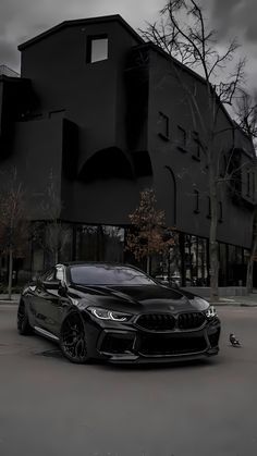 a black car is parked in front of a large building with dark clouds above it