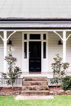 a white house with black front door and steps leading up to the entryway area