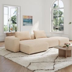 a living room filled with furniture and windows next to a white rug on top of a hard wood floor