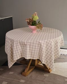 a pink bowl with flowers sitting on top of a wooden table next to a rug