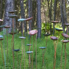 several metal flowers in the middle of a forest