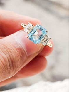 a woman's hand holding a ring with an aqua topazte and diamond