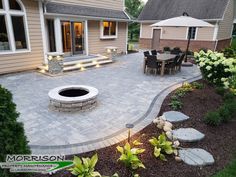 an outdoor patio with fire pit surrounded by landscaping