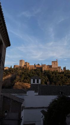 a castle on top of a hill with trees in the foreground and buildings below