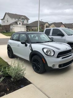 a white mini cooper parked in front of a house