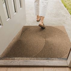 a woman is stepping on the door mat