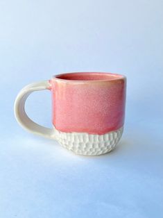 a pink and white coffee cup sitting on top of a table