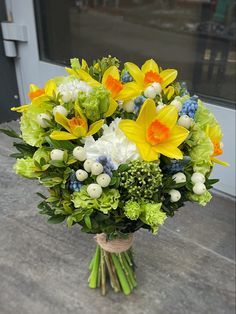 a bouquet of flowers sitting on top of a wooden table next to a building door