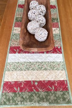 a wooden bowl filled with cookies sitting on top of a table next to a red and green place mat