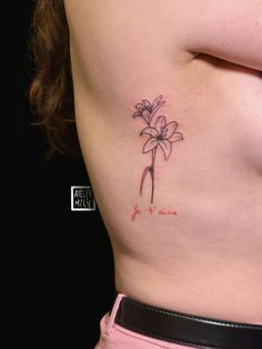 a woman's stomach with a small flower tattoo on her left side ribcage