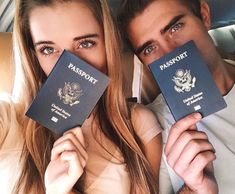 a man and woman holding up two passports in front of their faces while sitting in a car