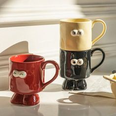 two coffee mugs with googly eyes are sitting on a counter next to each other