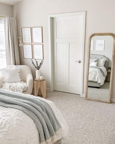 a bedroom with a bed, chair and mirror