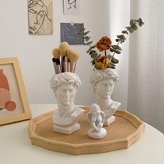 there are two statues with makeup brushes in their heads on the tray next to them