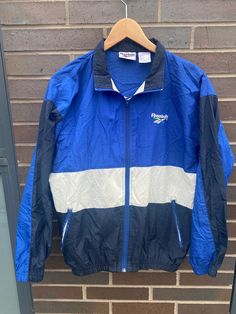 "Vintage 1990s Reebok Blue Windbreaker Jacket - Size XL (Length 25\", Chest 21\") - Fits like a MEDIUM - Great vintage condition (no holes/no stains) - Message for more information Follow our page for more vintage clothing drops!" 90s Style Sports Outerwear With Crew Neck, 90s Style Sports Windbreaker For Fall, 90s Style Fall Sports Windbreaker, Blue Retro Windbreaker For Streetwear, 90s Blue Track Jacket For Sports, Vintage Blue Track Jacket For Streetwear, Reebok Jacket, Retro Blue Nylon Windbreaker, Blue Windbreaker