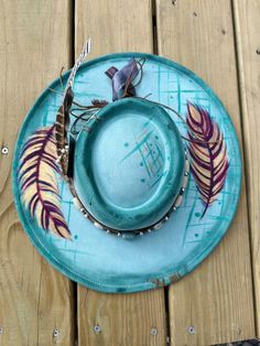 This teal western feather hat embodies a unique blend of artistry and western flair. This hat was meticulously hand-painted and hand-burned to create an exquisite feather design that is both stylish and authentic. The striking teal color adds a modern twist to the traditional western hat, making it a standout piece for any cowgirl or cowboy. Crafted with attention to detail, this hat is a true masterpiece that captures the essence of the wild west with a contemporary touch. Whether you're hitting the rodeo or simply embracing your cowboy spirit, this teal western feather hat is a must-have accessory that exudes character and charm. Stand out from the crowd and showcase your individuality with this one-of-a-kind handcrafted western hat. If you'd like completely custom design on a hat please Handmade Western Mini Hats For Kentucky Derby, Handmade Western Costume Hats And Headpieces For Western-themed Events, Handmade Western Costume Hats And Headpieces, Handmade Western Hats For Kentucky Derby, Artisan Feathered Festival Hat, Handmade Western Costume Hats For Kentucky Derby, Bohemian Costume Hats With Short Brim For Western-themed Events, Artisan Felt Hat For Kentucky Derby, Artisan Feather Hat For Festivals