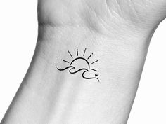 a small sun and wave tattoo on the wrist is shown in black ink with white background