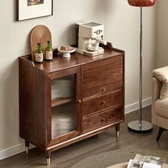 a living room with a couch, chair and coffee maker on the sideboard in it