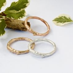 three different types of rings sitting on top of a white table next to green leaves