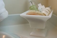 a bathroom sink with soap, toothbrush and lotion bottles in the bowl on it