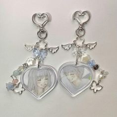 two heart shaped key chains with charms attached to them, one has an angel and the other is a flower