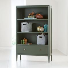 a green bookcase with baskets and books on it