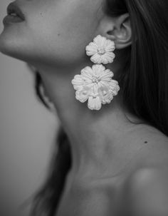 a close up of a person wearing large earrings with flowers on the back of their ear