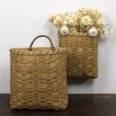 two woven baskets with flowers in them on a table