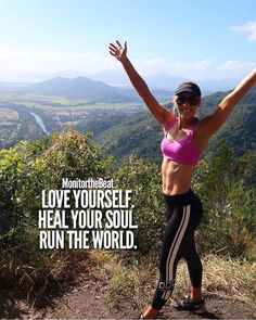 a woman standing on top of a mountain with her arms in the air