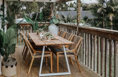 a wooden table sitting on top of a wooden deck next to a potted plant