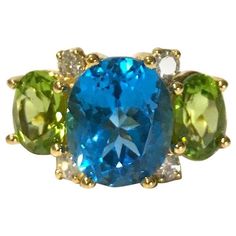 "Medium 18kt yellow gold GUM DROP™ ring with center Blue Topaz (approximately 8 cts), Peridot side stones (approximately 5 cts each), and 4 diamonds weighing 0.40 cts.  Specifications: Length:  ~ 1\" across the top and \"3/8\" from the bottom of the carriage mounting to the top of the center Blue Topaz.     The ring can be sized or ordered to your ring size.  The GUM DROP™ Ring Collection can be made in any color stone combination in either Yellow White or Rose gold.  Please contact me with any Gum Drop, Drop Ring, Ring Collection, Color Stone, Ring Collections, Blue Topaz, Or Rose, Yellow White, Clip On Earrings