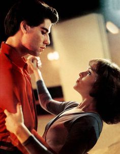 a man and woman dancing together in a dance studio with lights on the ceiling behind them