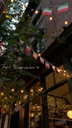 the outside of a restaurant with flags hanging from it's windows and lights on the ceiling