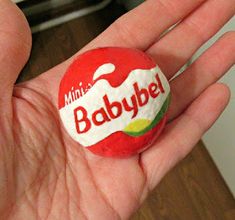 a hand holding a candy ball with the word babybel on it