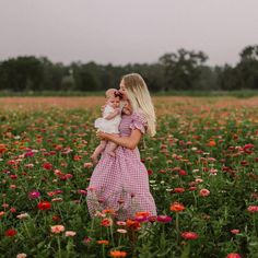 a woman holding a baby in a field of flowers