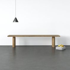 a wooden table sitting on top of a gray floor next to a book and lamp