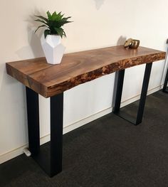 a wooden table with metal legs and a potted plant