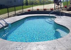 an empty swimming pool in front of a fenced yard with stairs leading up to it