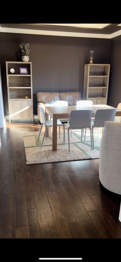 a living room filled with furniture and a white table in front of a bookshelf