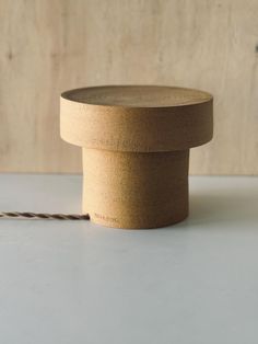 a wooden object with a rope on the ground next to it and a wall in the background